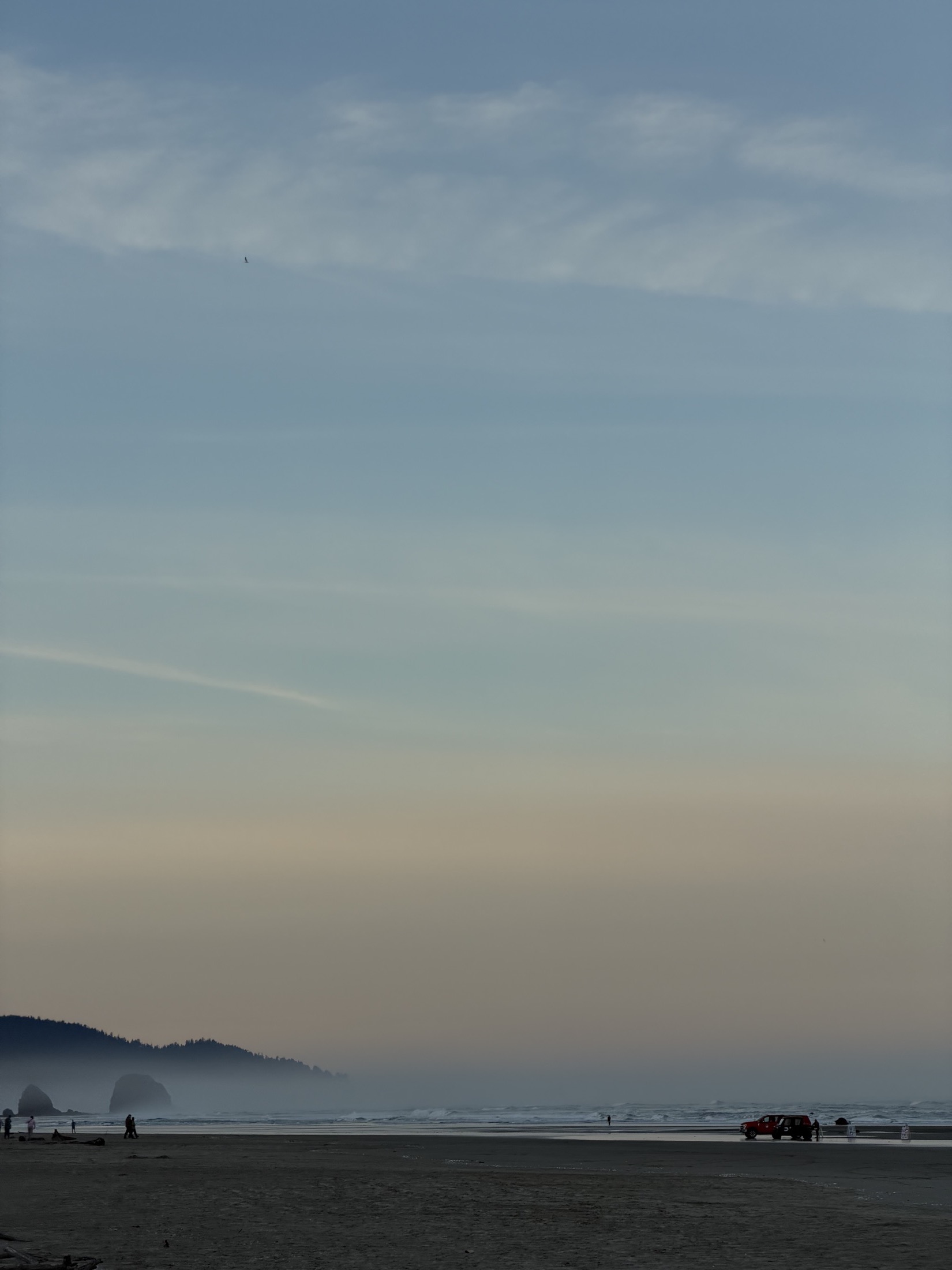 Hazy beach at sunset with distant figures